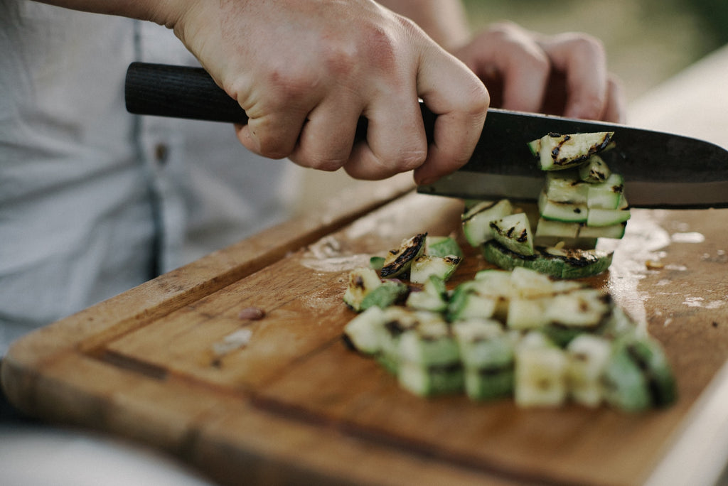 Santoku knife cutting courgettes on a wooden board